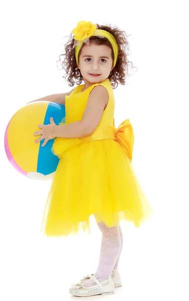 Κοριτσάκι σε κίτρινο φόρεμα κρατώντας μια μπάλα — Φωτογραφία Αρχείου