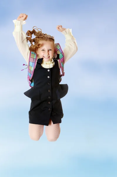 Girl schoolgirl with a satchel behind shoulders jumps — Stock Photo, Image