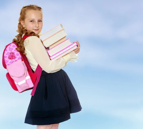 Flicka skolflicka med en skolväska bakom axlar och böcker i han — Stockfoto