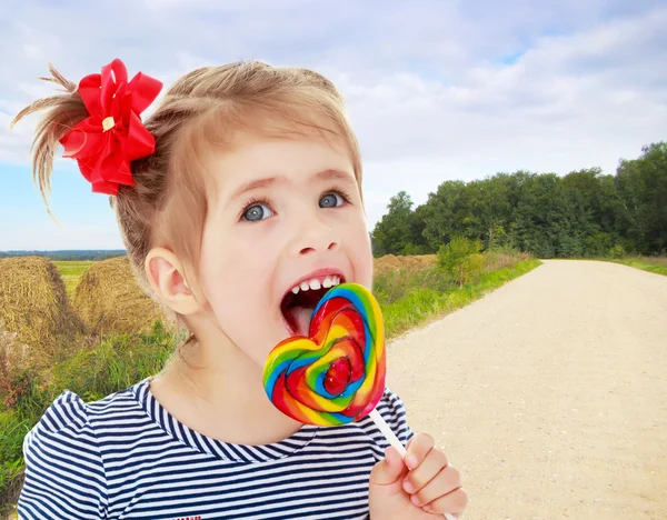 Girl licks candy on a stick — Stock Photo, Image