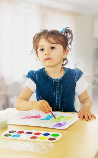 Küçük kız masada suluboya ile boyar. — Stok fotoğraf