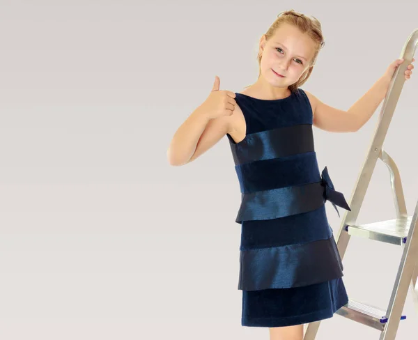Klein meisje staat op de trap en toont duim. — Stockfoto