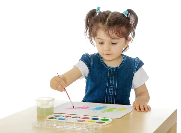 Niña pinta con acuarelas en la mesa . — Foto de Stock