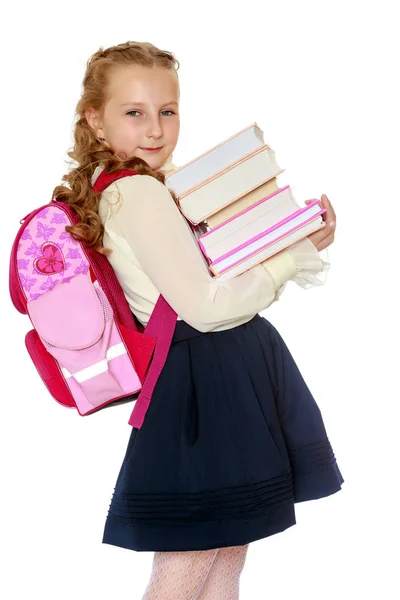 Chica colegiala con una cartera detrás de los hombros y libros en han — Foto de Stock