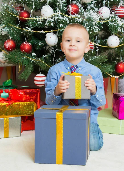 Мальчик с подарками возле елки — стоковое фото