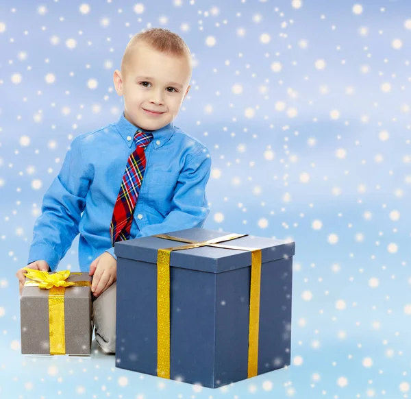 De kleine jongen kijkt naar het vak met de geschenken — Stockfoto