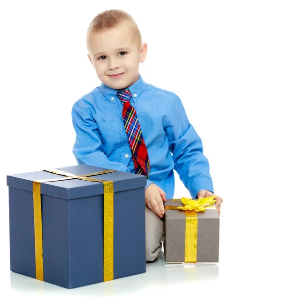 De kleine jongen kijkt naar het vak met de geschenken — Stockfoto