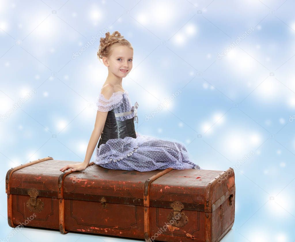 Little girl sitting on a suitcase.