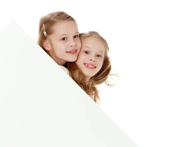 Little girls look out from behind the banner. — Stock Photo, Image