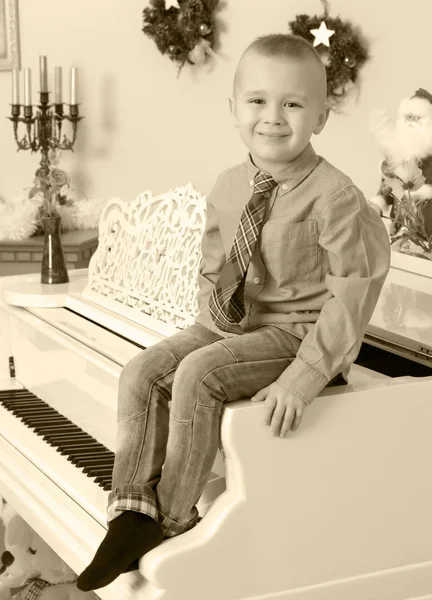 Chłopiec siedzi na biały fortepian — Zdjęcie stockowe