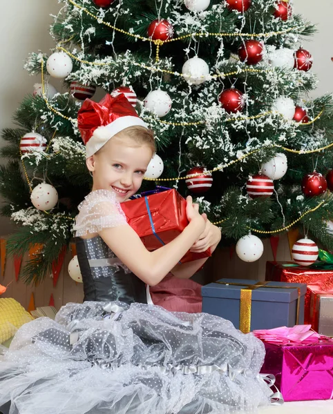큰 선물 크리스마스 트리 근처에 앉아 어린 소녀. — 스톡 사진