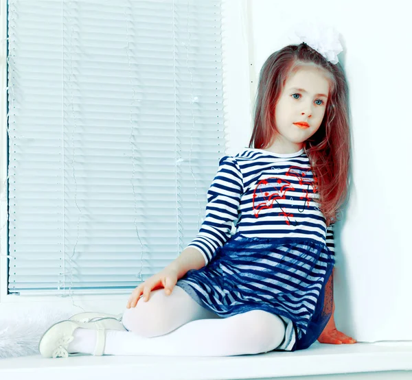 Triste petite fille assise près de la fenêtre . — Photo