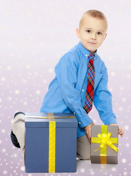 El niño mira la caja con los regalos. — Foto de Stock