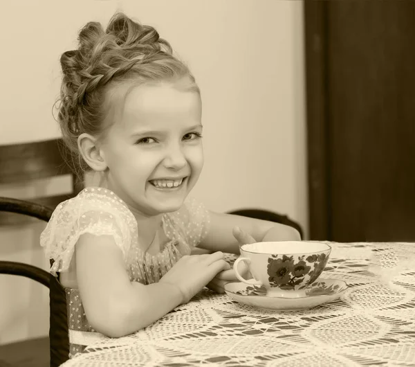 Schattig klein meisje thee drinken bij de oude tabel. — Stockfoto