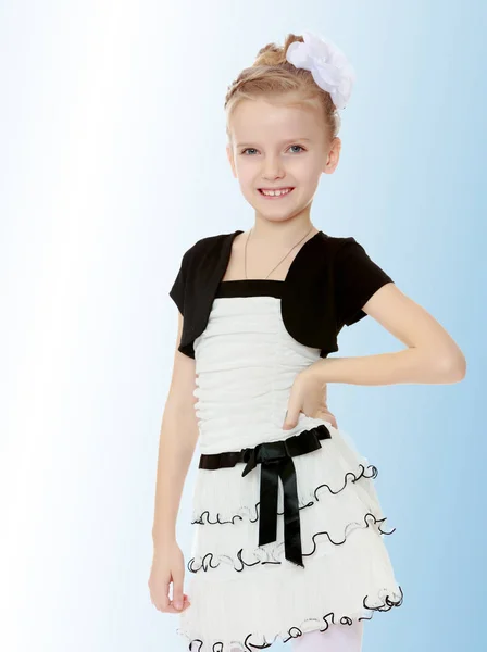 Schönes kleines Mädchen in einem weißen kurzen Kleid mit schwarzem Gürtel. — Stockfoto