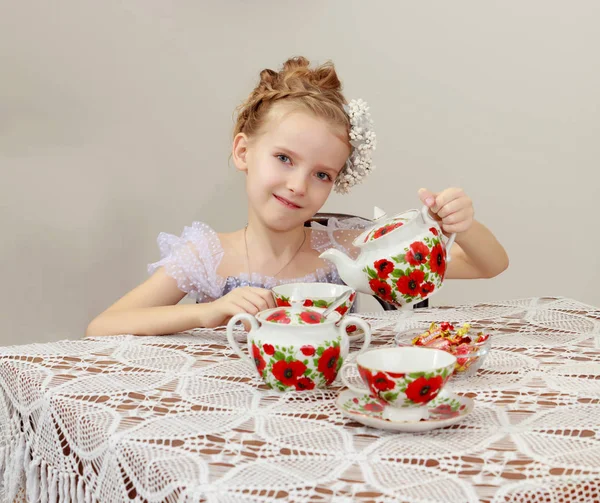 Schattig klein meisje thee drinken bij de oude tabel. — Stockfoto