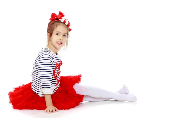 Malá holčička v červené sukni a mašlí na hlavě. — Stock fotografie