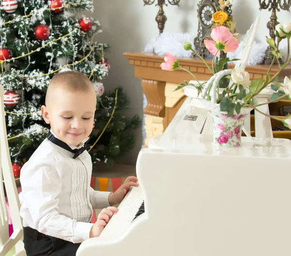 Маленький мальчик играет на белом рояле . — стоковое фото