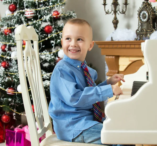 Маленький мальчик играет на белом рояле . — стоковое фото