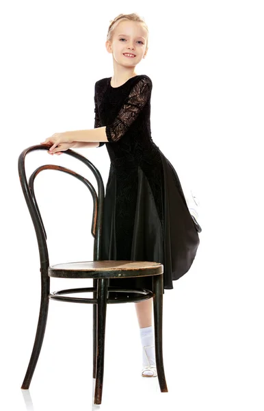 Schlanke kleine Tänzerin posiert in der Nähe des alten Wiener Stuhls. — Stockfoto