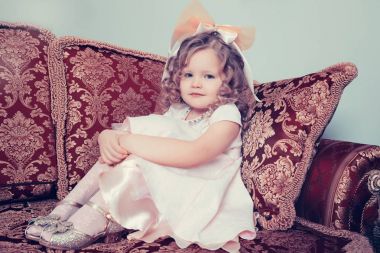 Elleriyle dizlerinin sarılma kanepede oturan kız.