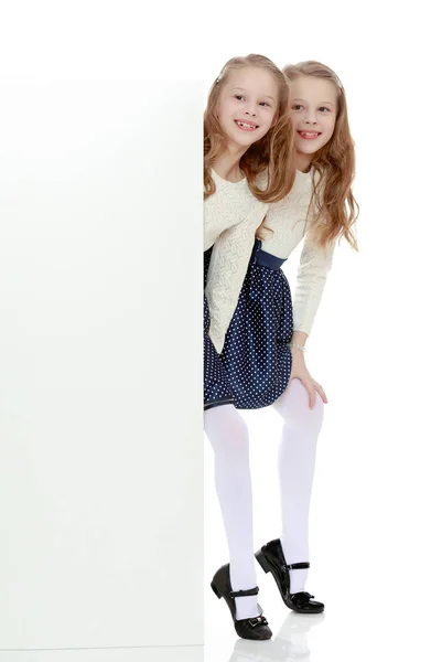 Little girls look out from behind the banner. — Stock Photo, Image