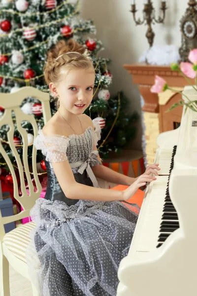 Mała dziewczynka gra na biały fortepian. — Zdjęcie stockowe