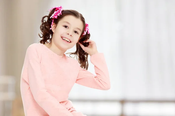 Menina sentada no chão e endireita o cabelo . — Fotografia de Stock