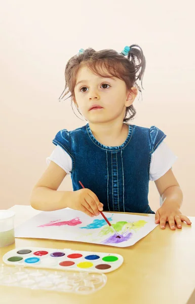 Menina pinta com aquarelas na mesa . — Fotografia de Stock