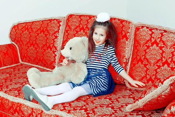 Meisje zittend op de Bank met teddybeer. — Stockfoto