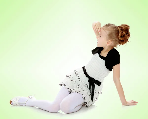 Girl sitting on the floor leaning on hand and looking to the sid — Stock Photo, Image