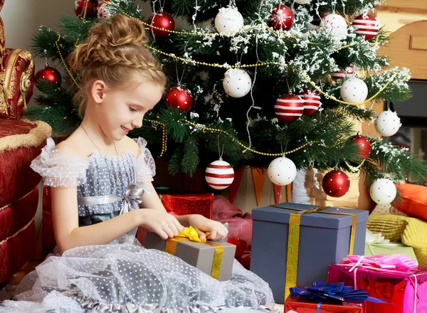 Little girl with a gift near the Christmas tree. — Stock Photo, Image