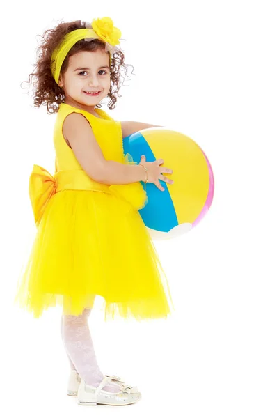 Bambina in abito giallo con una palla in mano — Foto Stock