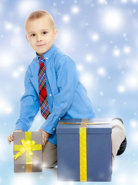 De kleine jongen kijkt naar het vak met de geschenken — Stockfoto