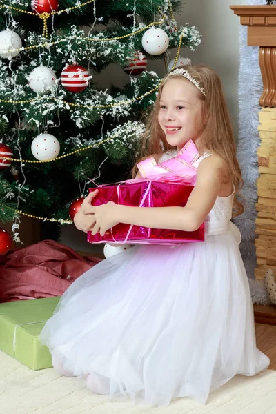 Kleine Prinzessin mit einem Geschenk am Weihnachtsbaum. — Stockfoto