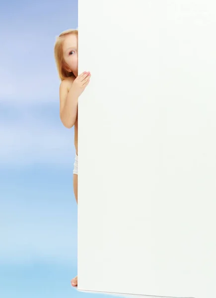 Маленькая девочка выглядывает из-за плаката . — стоковое фото