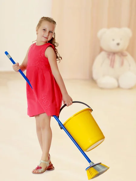 Little girl with bucket and brush cleans the house.