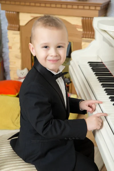 Мальчик сидит за белым пианино . — стоковое фото