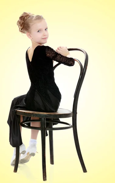 Pequeña bailarina delgada posando cerca de la vieja silla de Viena . — Foto de Stock