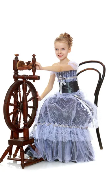 Little girl sitting at a spinning wheel. — Stock Photo, Image