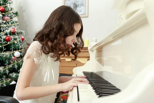 Piyanonun oturan beyaz elbiseli güzel kız. — Stok fotoğraf