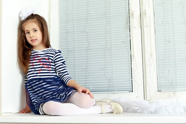 Sad little girl sitting by the window. — Stock Photo, Image