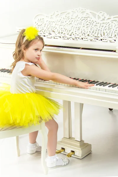 Triste menina sentada apoiada em um piano branco Grand . — Fotografia de Stock