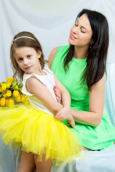 Mãe e filha no sofá com um buquê de flores . — Fotografia de Stock