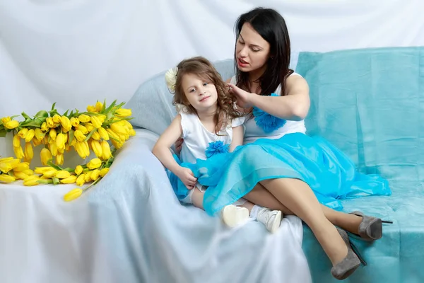 妈妈和女儿在沙发上用一束鲜花. — 图库照片