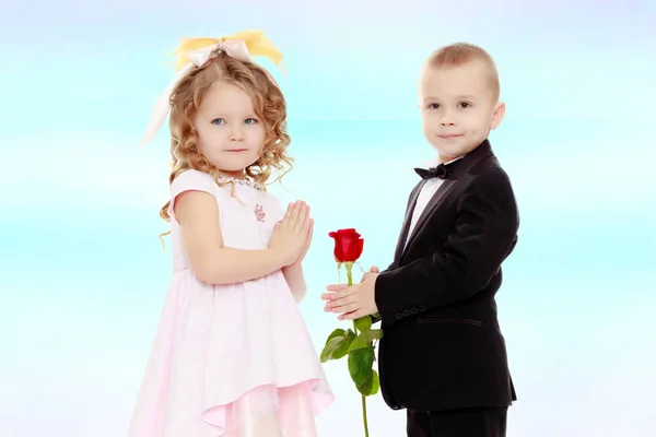 Pojken ger flickan en blomma. — Stockfoto