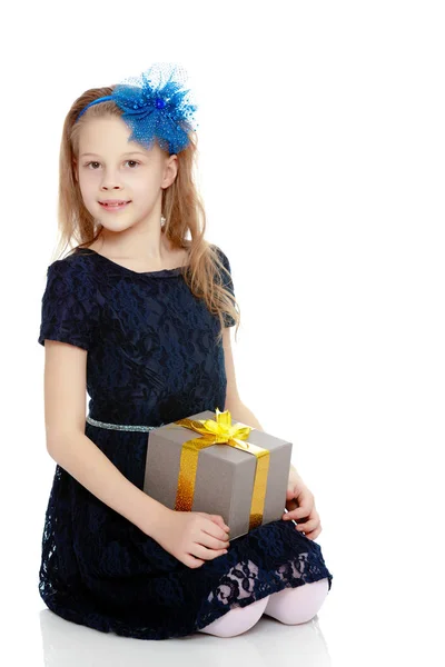Schattig klein meisje met een gift in de hand. — Stockfoto