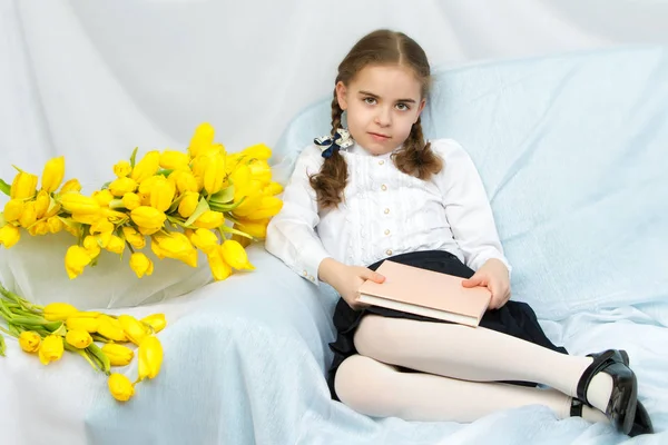 Um estudante estudante diligente com tulipas amarelas está sentado em t — Fotografia de Stock