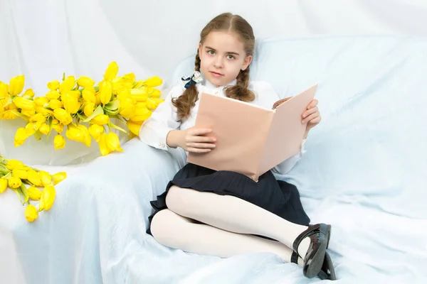 En flitig Skolflicka student med gula tulpaner sitter på t — Stockfoto