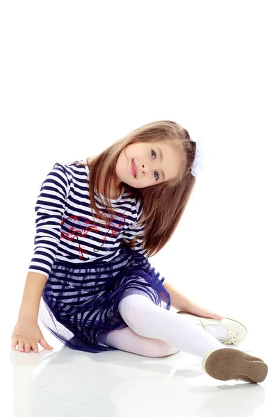 Klein meisje zit op de vloer. — Stockfoto